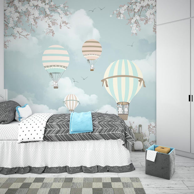 Kids' room with pastel hot air balloon wall mural featuring clouds, cherry blossoms, and a cozy bed with playful decor.