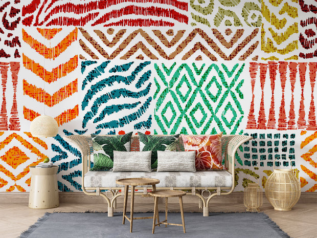 Colorful tribal pattern wall mural with teal, orange, and green geometric designs, styled in boho living room with rattan furniture.