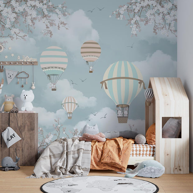 Kids' room with pastel hot air balloon wall mural featuring clouds, cherry blossoms, and a cozy wooden bed with playful decor.