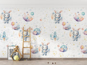 Space-themed wall mural with bunnies in astronaut suits, colorful planets, rockets and stars, decorating a cozy kid's playroom.