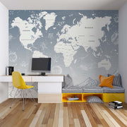 Modern gray world map wall mural with space elements, styled in contemporary children's study area with yellow accents and built-in seating.