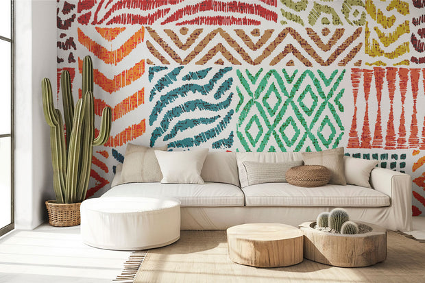 Colorful tribal pattern wall mural with teal, orange, and green geometric designs, styled in modern living room with sofa.