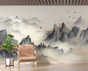 A tranquil living room featuring a Tranquil Peaks Wall Mural with misty watercolour mountains and golden foliage. Styled with wooden armchair  and lush plants, creating a serene and nature-inspired atmosphere.