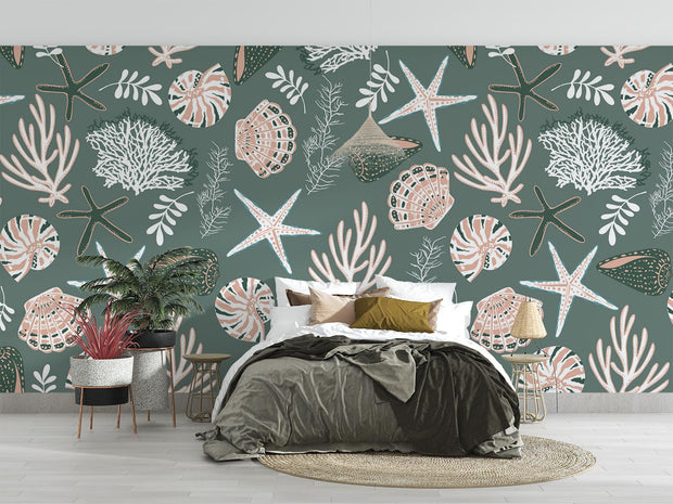 Coastal wall mural featuring starfish, seashells, coral reefs, and marine plants in soft pastel tones on a muted green background, decorating a bedroom.