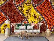 Bold tropical wall mural with vibrant orange, yellow, and brown leaf patterns, accented with white dots, perfect for boho and eclectic interior decor.