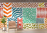 Colorful tribal pattern wall mural with teal, orange, and green geometric designs, styled in living room with a blush chair.