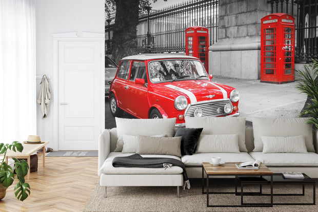 Wall mural showcasing a vibrant red Mini Cooper and iconic red telephone boxes in a black-and-white London city scene; decorating a living room.