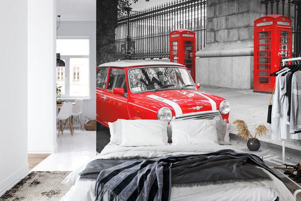 Wall mural showcasing a vibrant red Mini Cooper and iconic red telephone boxes in a black-and-white London city scene; decorating a bedroom.