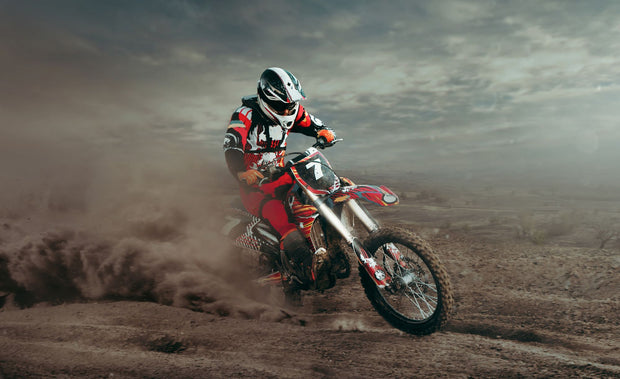 Wall mural featuring a dirt bike racer in mid-action on a desert track, surrounded by dust and rugged terrain.