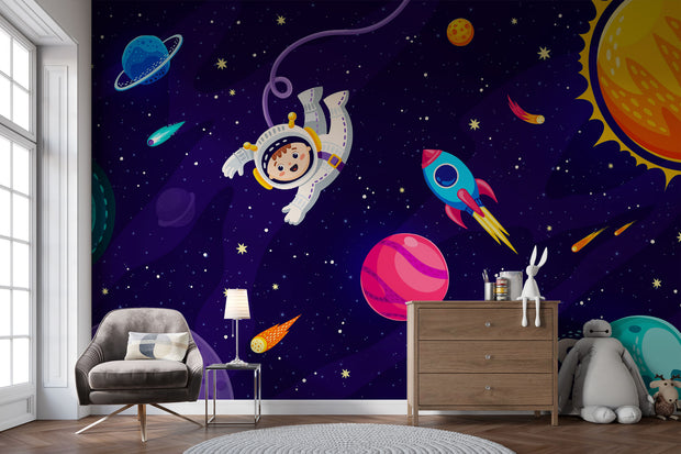 Cosmic explorer wall mural with cartoon astronaut, rocket ship, planets, and starry galaxy background in a playful kids’ bedroom.
