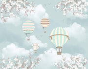 Pastel hot air balloon wall mural featuring clouds, cherry blossoms, and a cozy wooden bed with playful decor.