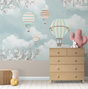 Nursery with pastel hot air balloon wall mural featuring clouds, cherry blossoms, and a cosy playful decor.