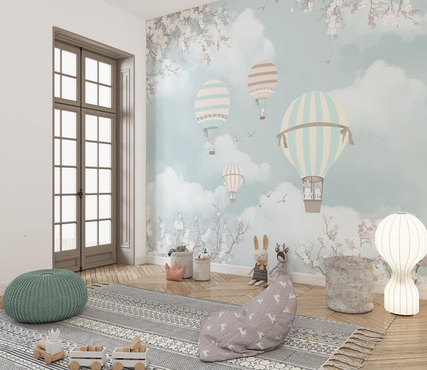 Kids' playroom with pastel hot air balloon wall mural featuring clouds and cherry blossoms.