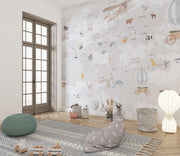 Whimsical world map wall mural featuring illustrated continents, animals, vintage airplanes, and hot air balloons, styled in a modern kids' room.